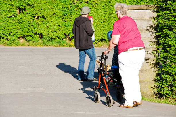 un'anziana donna con un deambulatore che si gode una passeggiata estiva in un parco pubblico a dortmund - germania - house wood dirt road footpath foto e immagini stock