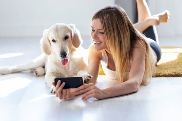 istock Pretty young woman with her dog using mobile phone while lying on the floor at home. 1171367471
