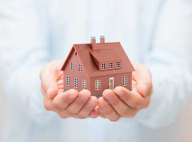 istock Small brown toy house in hands 1171367478