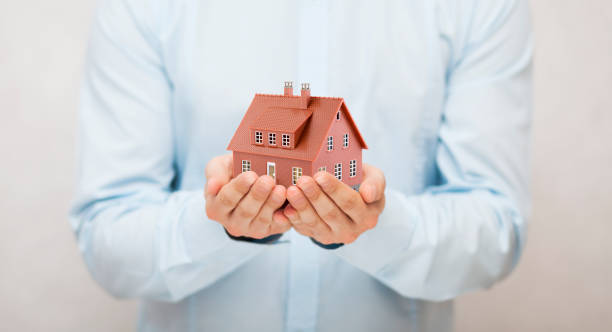 istock Small brown toy house in hands 1171367613