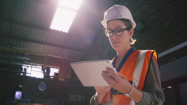 産業用職場でデジタルタブレットを使用した若手エンジニアの4kビデオ映像
