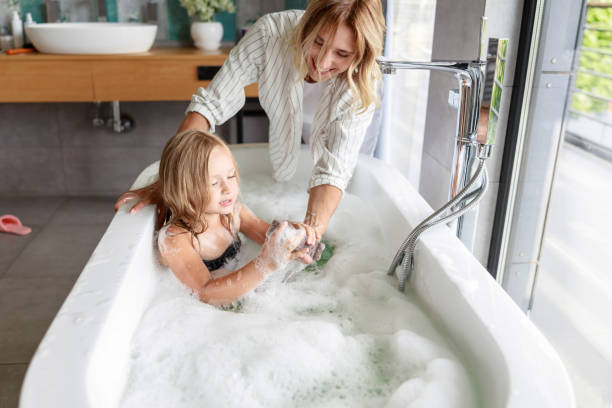 istock Smiling mom feeding shower sponge to daughter 1171380450