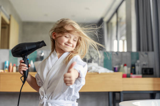 Cute girl closing her eyes in the bathroom Little smiling girl giving thumbs up stock photo blow drying stock pictures, royalty-free photos & images