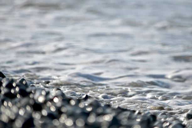 istock Swirling bokeh corner with sea pebbles and sea. 1171389103