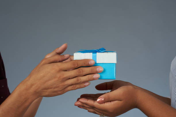 Close up view of giving gift box to woman hands