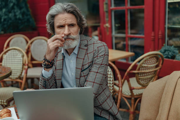 istock Elegant senior man with laptop touching his mustache 1171390749