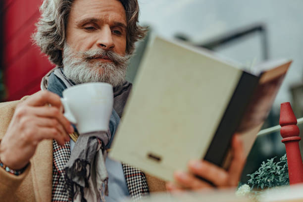 istock Handsome senior man reading book at outdoor cafe 1171390779