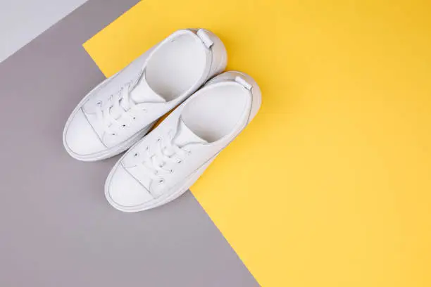 Photo of Pair of fashionable sneakers on a gray and yellow background.