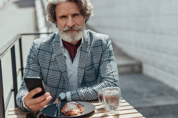 istock Handsome senior man using mobile phone at outdoor cafe 1171393625