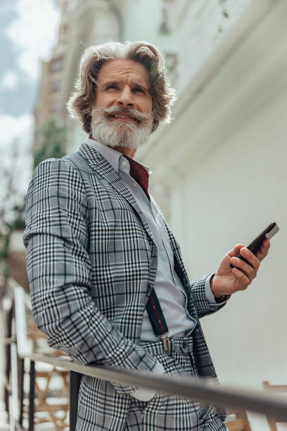 istock Joyful bearded gentleman is using cellphone outdoors 1171393660