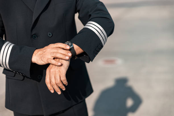 istock Caucasian pilot in uniform looking at watch in airport 1171400448