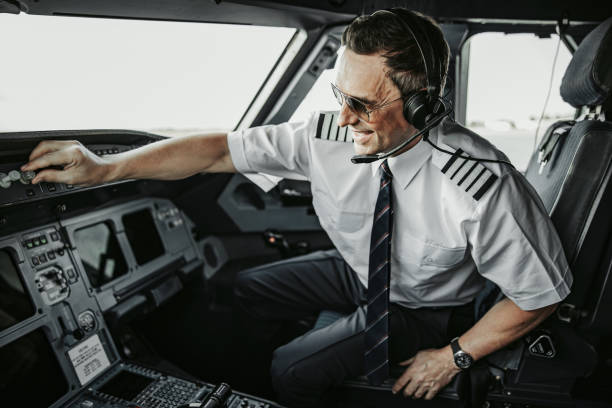 uomo adulto felice caucasico in uniforme pilotando un aereo perfettamente moderno - pilotando foto e immagini stock