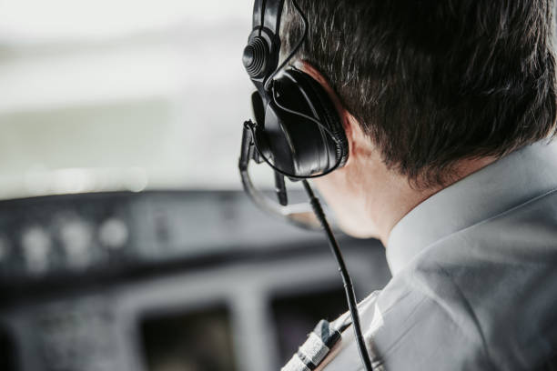 uomo caucasico in cuffia pilotando un moderno aereo di linea - pilotando foto e immagini stock