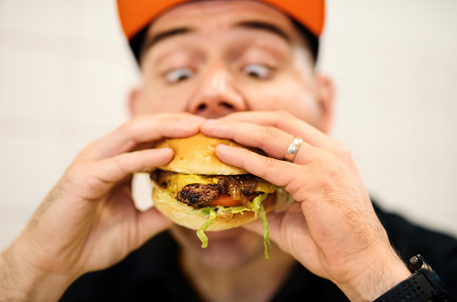 Close up of a hungry man biting fresh tasty hamburger