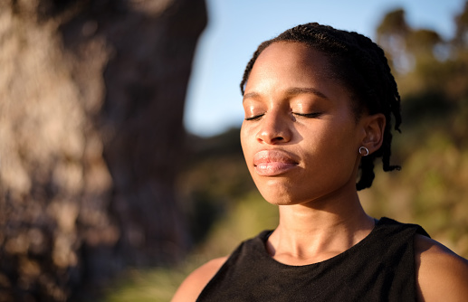 Close-up shot of healthy young woman meditating outdoors with her eyes closed