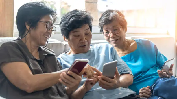 Photo of Aging society concept with Asian elderly senior adult women sisters  using mobile digital smart phone application technology for social media network among friends community via internet communication