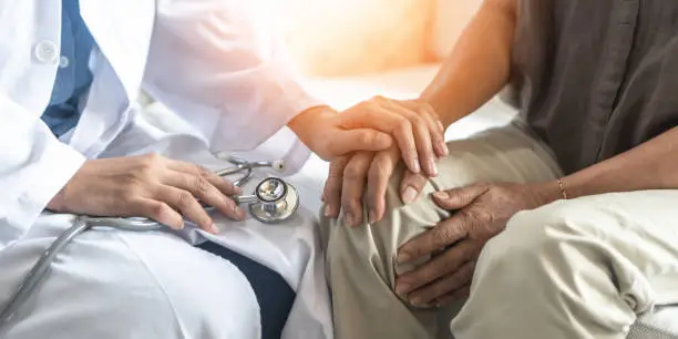 Photo of Parkinson's disease patient, Arthritis hand and knee pain or mental health care concept with geriatric doctor consulting examining elderly senior aged adult in medical exam clinic or hospital