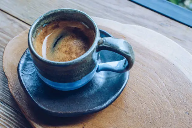 Photo of A cup of hot espresso shot on the wooden table.