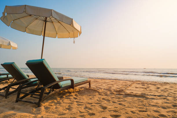 istock Sun umbrellas and chairs on tropical beach with sunset 1171427077