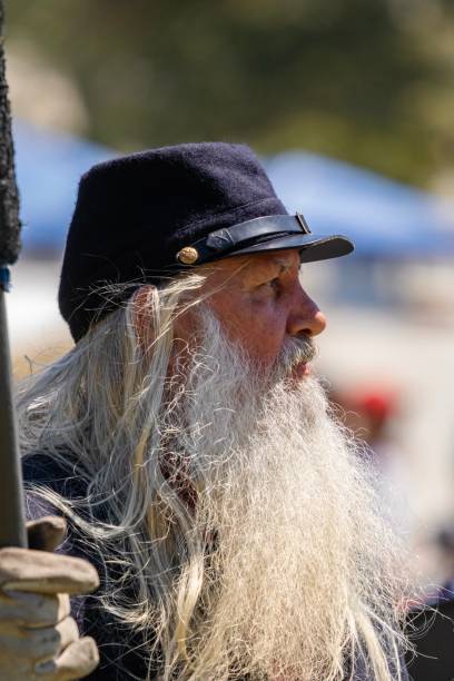 Civil war soldier during a Civil War re-enactment August 31, 2019, Huntington Beach California - Profile of a man with a long white beard dressed in Civil War era clothing during the Civil War reenactment civil war enactment stock pictures, royalty-free photos & images