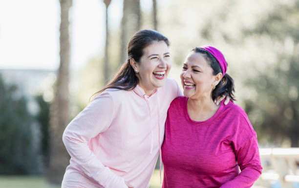 二人の成熟したヒスパニックの女性が一緒に笑う - focus on foreground joy happiness pink ストックフォトと画像