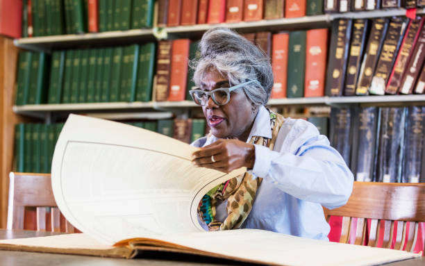 istock Woman doing research in library looking at old book 1171430483