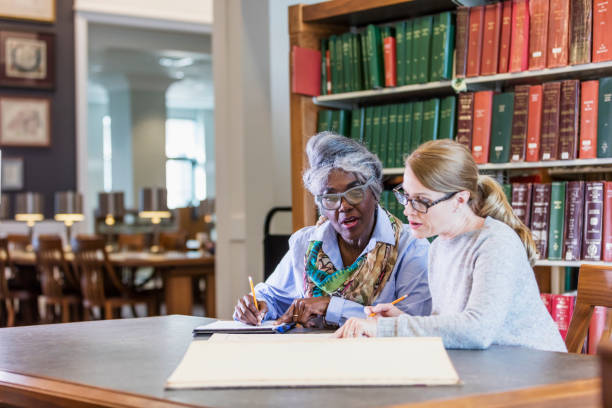 istock Two women doing research in the library together 1171430510