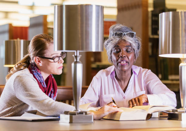 istock Two women doing research in the library together 1171431255
