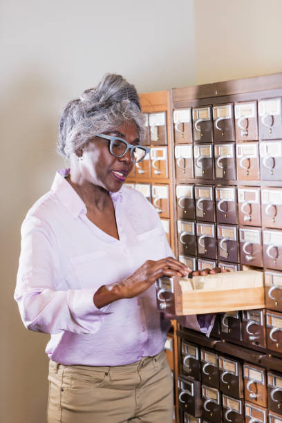 istock Senior woman in library looking through card catalog 1171431380