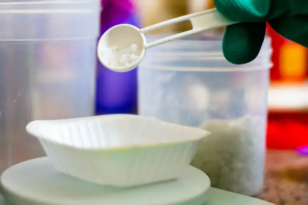 Photo of Lye caustic soda being measured out on weighing scale for making soap