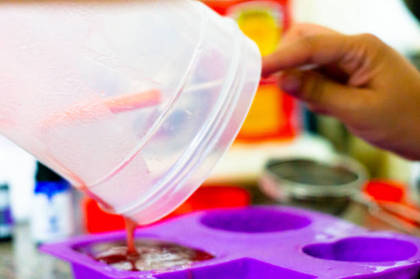 istock Soap solution being poured from a plastic container into a silicone mold for home made soap 1171435109