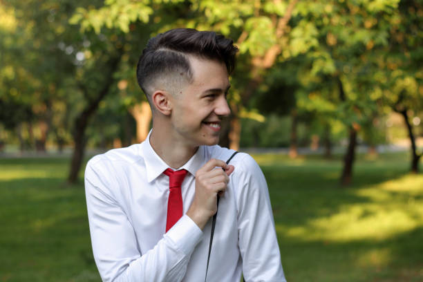 istock Stylishly dressed young man posing in a park. Laughs and adjusts the strap on the shoulder of the camera. 1171436713