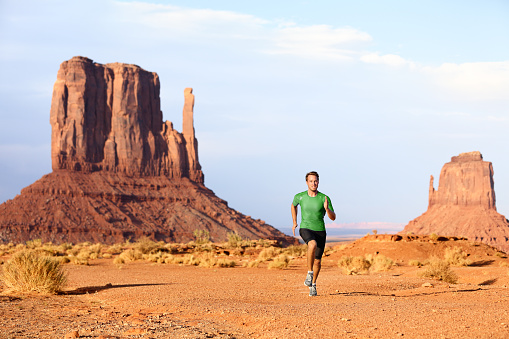 Runner. Running man sprinting in Monument Valley. Athlete runner cross country trail running outdoors in amazing nature landscape. Fit male sports model in fast sprint at speed, Arizona Utah, USA.
