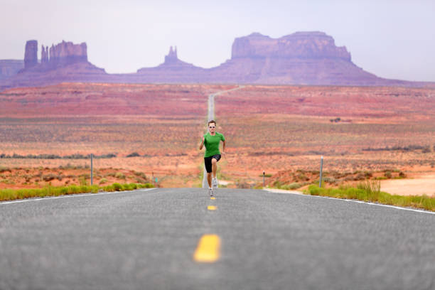 running man - corridore su strada vicino a monument valley - arizona desert landscape monument valley foto e immagini stock