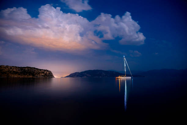 a sailboat reflected in the lights of the sea - water lake reflection tranquil scene imagens e fotografias de stock