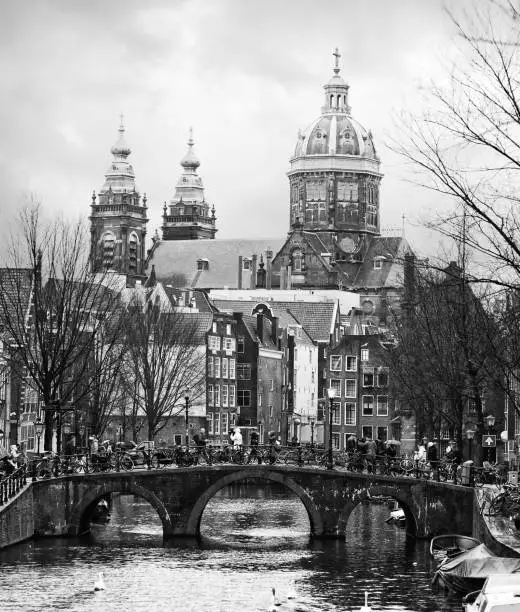 Oudezijds Voorburgwal canal  in the center of Amsterdam. In the background Basilica of St. Nicholas. Black and white