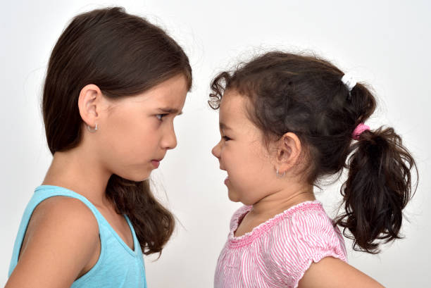Two angry sisters quarreling Two angry sisters standing face to face, quarreling and looking at each other only girls stock pictures, royalty-free photos & images