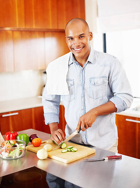 istock Happy, young man chopping cucumber in kitchen 117144442