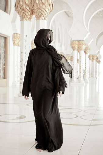 young muslim woman in abaya, walking through mosque.