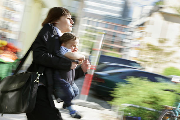 Working in a rush, mom carrying infant son outdoors stock photo
