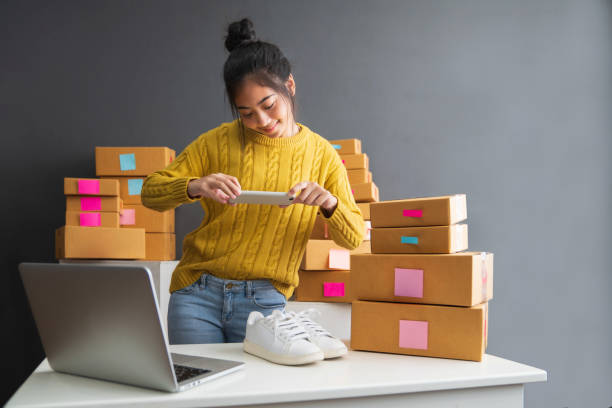 giovani donne che scattano foto alle scarpe con cellulare o fotocamera digitale per smartphone per posta da vendere online su internet e preparano la confezione del prodotto. concetto di vendita di idee online - internet sales foto e immagini stock