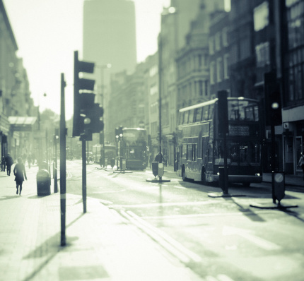 City of London. Early morning, Oxford Street with typical Double Deck Busses and people walking around.  Monochrome, toned in green and orange. Grainy and flares to emphasize the mood.