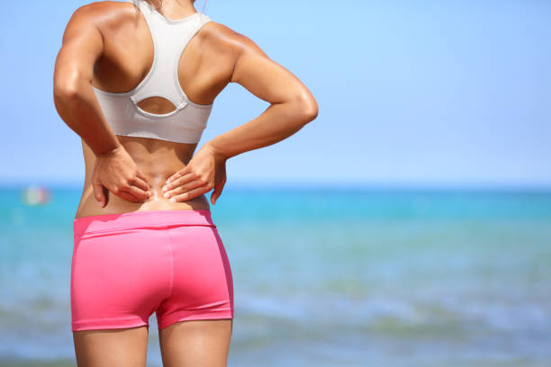 боль в спине - спортивная женщина потирая спину - human spine human age horizontal outdoors стоковые фото и изображения