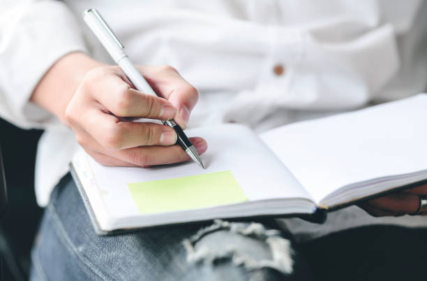 istock Close up of man hands holding pen writing on notebook. 1171450388