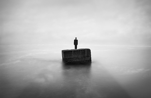 Man is thinking on the edge of  stone. Image was shot with long exposure, therefore water looks in this way. Only man was pasted and horizon was removed, other on the photo is original. Man was pasted from another image