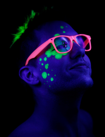 Portrait of man under black lights.  No filters were used to create this effect - this is UV lighting creating the glow in the  makeup and skin.  High ISO settings used.