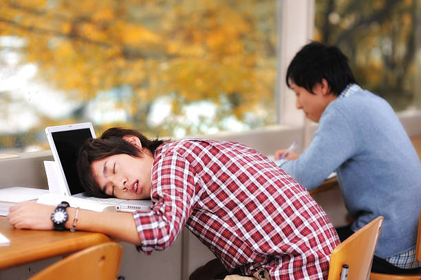 Two Asian students studying but one has fallen asleep College Student sleeping on his laptop when he should be studying. iStockalypse Tokyo 2010. male college student sleeping through lecture stock pictures, royalty-free photos & images