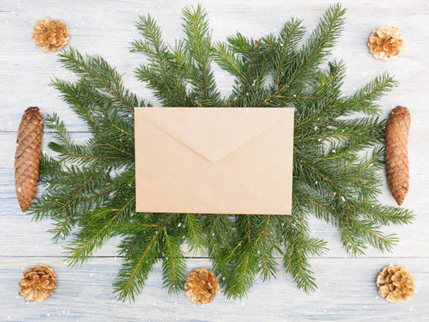 istock Fir tree branch with cones, envelope, snowflake on white wooden background. Winter holidays concept 1171455278