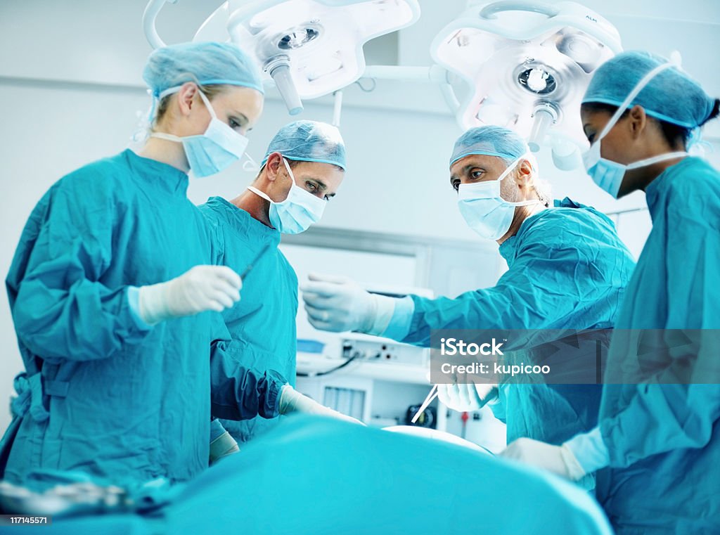 Group of surgeons in operating room  Adult Stock Photo