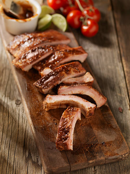 costelas de porco volta sobre uma tábua de cozinha - sparerib imagens e fotografias de stock